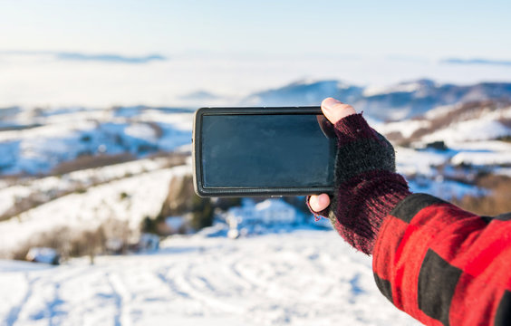 Man taking picture with a smart phone in the winter