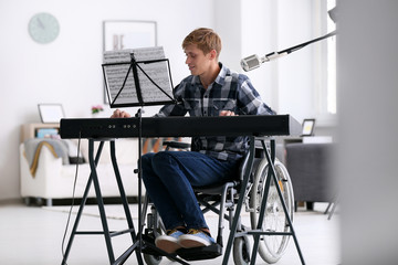 Young musician in wheelchair playing synthesizer at home
