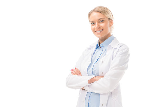 happy young female doctor with crossed arms looking at camera isolated on white