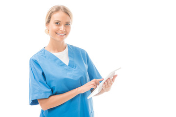 happy young nurse working with digital tablet and looking at camera isolated on white