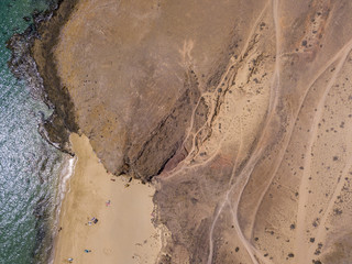 Vista aerea delle coste frastagliate e delle spiagge di Lanzarote, Spagna, Canarie. Strade e sentieri sterrati. Bagnanti in spiaggia e nell’Oceano Atlantico. Papagayo