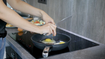 Crop woman frying eggs in pan