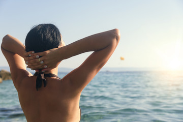 Young woman in bikini on the blue sea shore.