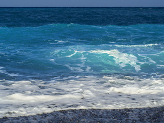 Naklejka na ściany i meble Beautiful foam waves on a sunny day in the Aegean Sea on the island of Evia in Greece