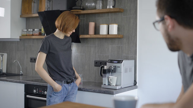 Casual woman making coffee with machine at home