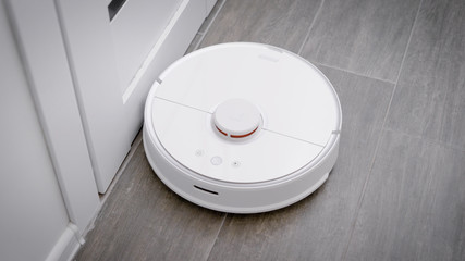 in the frame is a robot vacuum cleaner that cleans the floor in the kitchen.