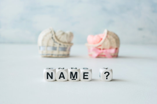 Concept of choosing baby name. Pink and blue decorative straw cradles with thread hearts and text name? on light background