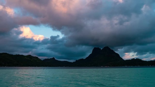 Timelapse footage of luxury overwater villas, blue lagoon, white sandy beach and Otemanu mountain during sunset at Bora Bora island, Tahiti, French Polynesia