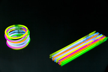 Colorful fluorescent light neon glow stick bracelet strap wristband on mirror reflection black...