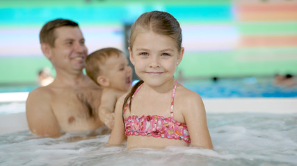 Family spending time in a resort's jacuzzi, relaxing in bubbling water.