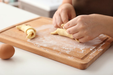 Woman preparing tasty croissants at table, closeup