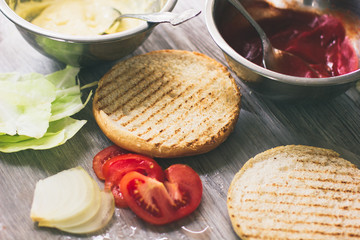 Homemade burger ingredients arranged on vintage wooden plate