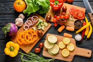 Cutting boards and many fresh vegetables on wooden background