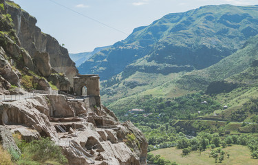 Naklejka premium Caves of the Vardzia monastery, Georgia. Rocky green mountains and grass covering the hills.