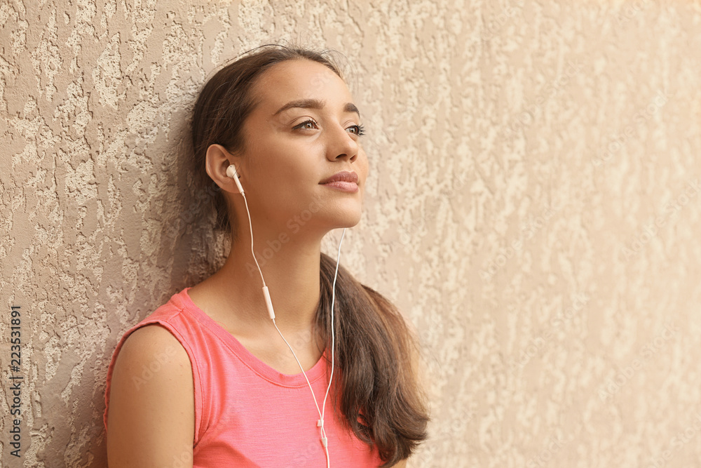 Poster Beautiful young woman listening to music near color wall