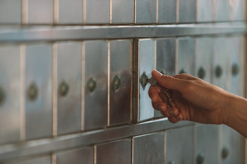 Close up of a female hand opening a mailbox with a small key - post office box or PO BOX concept -...