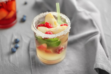 Glass of refreshing summer cocktail with fruits and berries on table