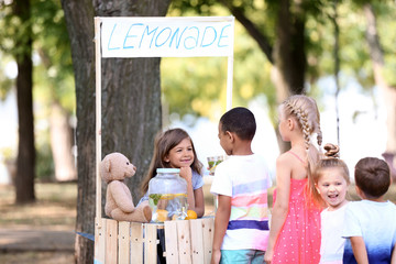 Adorable children waiting in queue for natural lemonade near stand in park - obrazy, fototapety, plakaty