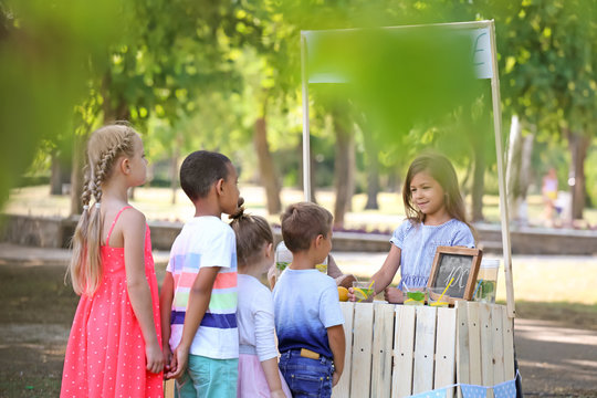 Adorable Children Waiting In Queue For Natural Lemonade Near Stand In Park