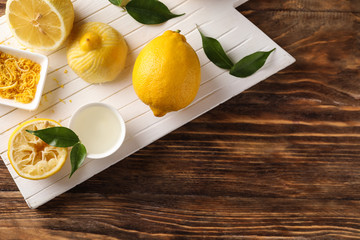Board with ripe lemons, zest and fresh juice on wooden table