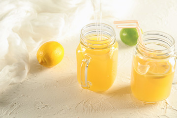 Mason jars of fresh lemon juice on white textured background