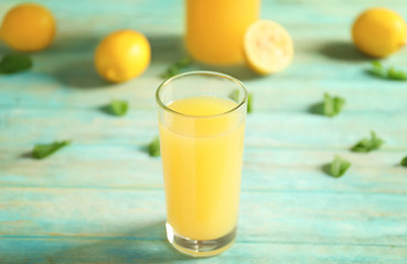 Glass of fresh lemon juice on light wooden table