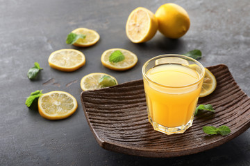 Glass of fresh lemon juice on grey table