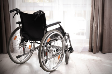 Empty modern wheelchair near window in room
