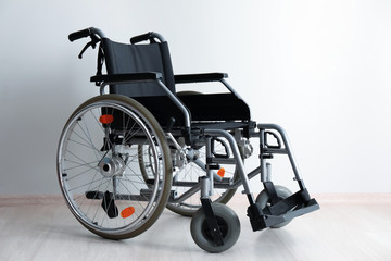Empty modern wheelchair against light wall