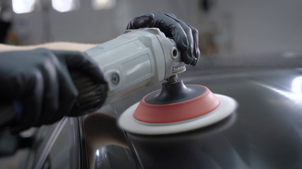 Close-up hands holding polishing machine and taking care of car