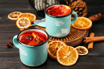 Metal cups of delicious mulled wine on wooden table