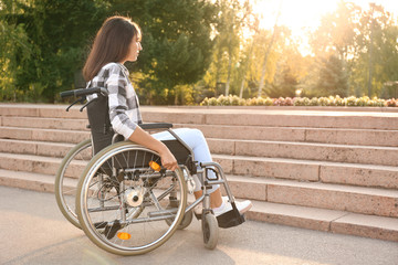 Young woman in wheelchair near stairs outdoors