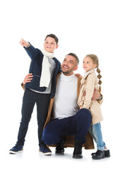 Fototapeta premium stylish father hugging kids in autumn outfit, boy showing something isolated on white