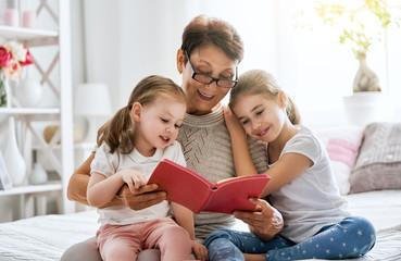 Grandmother reading a book to granddaughters