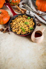 Homemade autumn pastries, pumpkin crumble pie in a cast-iron frying pan, light stone background, copy space top view