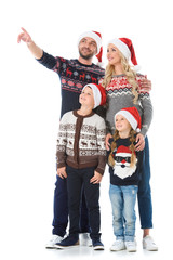 Fototapeta premium happy family with kids in christmas sweaters and santa hats, father showing something isolated on white