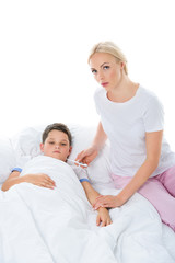 Fototapeta premium mother with electronic thermometer sitting near sick son, isolated on white