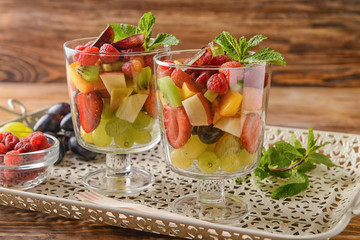 Glasses with delicious fruit salad and mint on tray