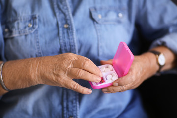 Senior woman holding container with pills, closeup