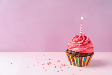 Delicious birthday cupcake with candle on color background