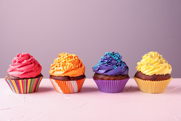 Delicious cupcakes on color background
