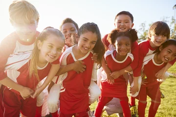 Tuinposter Kids in elementary school sports team piggybacking outdoors © Monkey Business