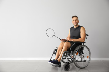Badminton player sitting in wheelchair against light wall