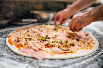 Putting the ingredients on the pizza.