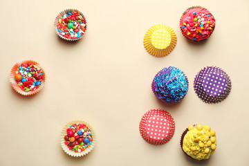 Tasty cupcakes and baking cups with sprinkles on light background