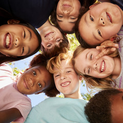 A huddle of school kids looking down at camera, close up