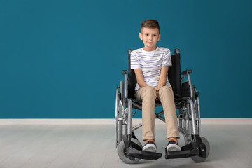 Boy in wheelchair against color wall