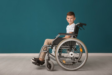 Boy in wheelchair against color wall