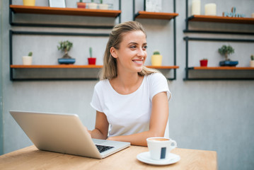 Smling girl with laptop looking away.