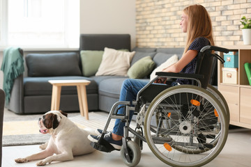 Fototapeta na wymiar Teenage girl in wheelchair and her dog at home